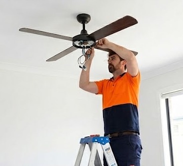 Electrician installing a ceiling fan in a Perth home