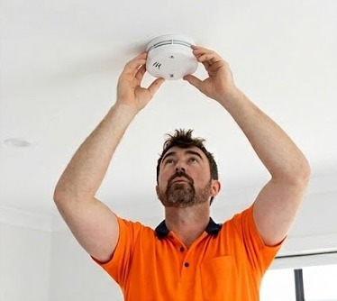 Electrician installing a hardwired smoke alarm